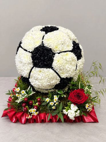 Floral arrangement shaped like a soccer ball with decorative flowers.