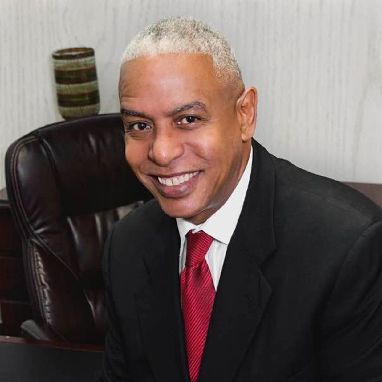 Smiling man in black suit with red tie.