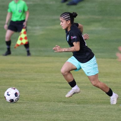 Soccer player sprinting towards the ball on the field.