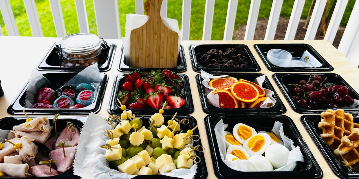 Assorted breakfast platter with fruits, cheese, eggs, meats, and waffles.