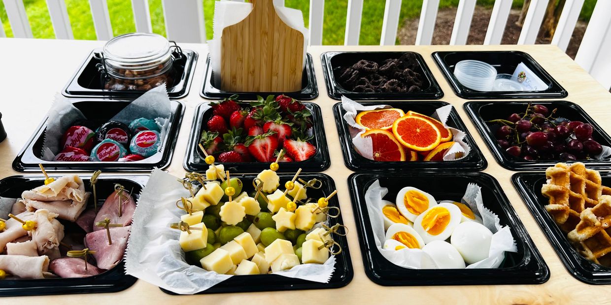 Assorted breakfast platter with fruits, cheese, eggs, meats, and waffles.