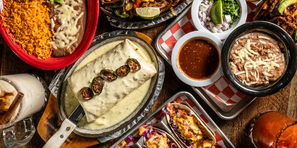A vibrant spread of Mexican dishes with rice, beans, tacos, and drinks.