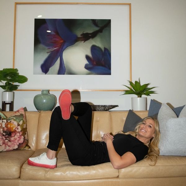 Woman relaxing on a tan couch with decorative pillows and plants.