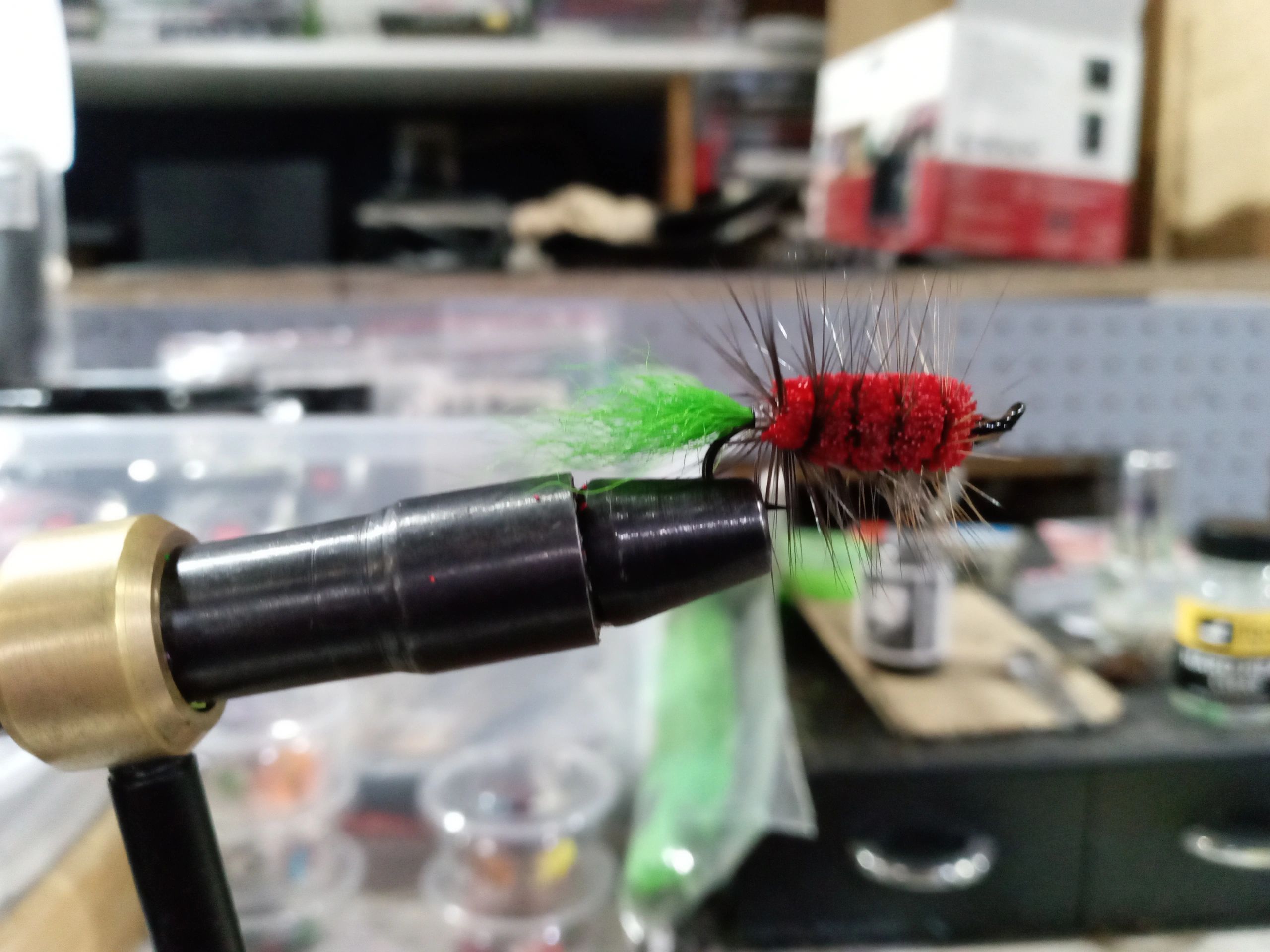 Close-up of a colorful fishing fly held in a vise for fly tying.