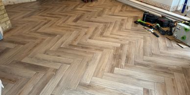 Newly installed herringbone wooden floor with tools nearby.