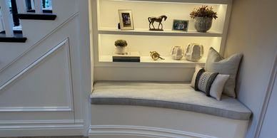 Cozy built-in window seat with cushions and decorative shelves.