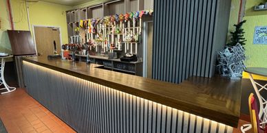 A bar counter with multiple beer taps and stylish lighting.