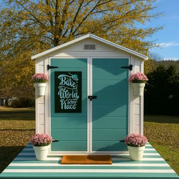 Cute teal shed with pink flowers and a motivational sign outside.