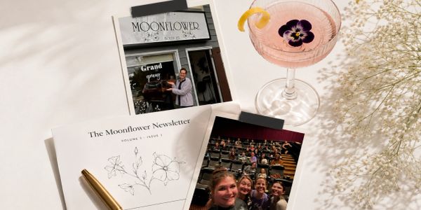 A styled flat lay with newsletters, a cocktail, and a group photo.
