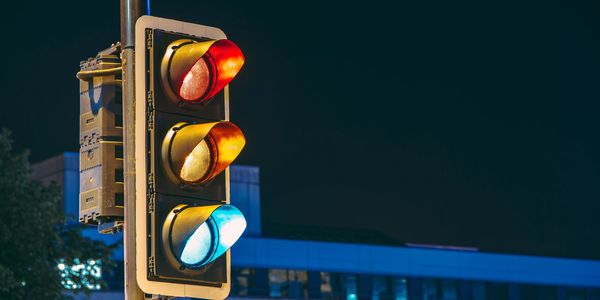Traffic lights glowing red, yellow, and blue at night in an urban setting.