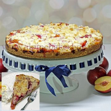 Peach crumb cake on a stand with a slice served with cream.
