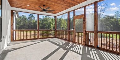 Spacious screened porch with wooden ceiling and railings.