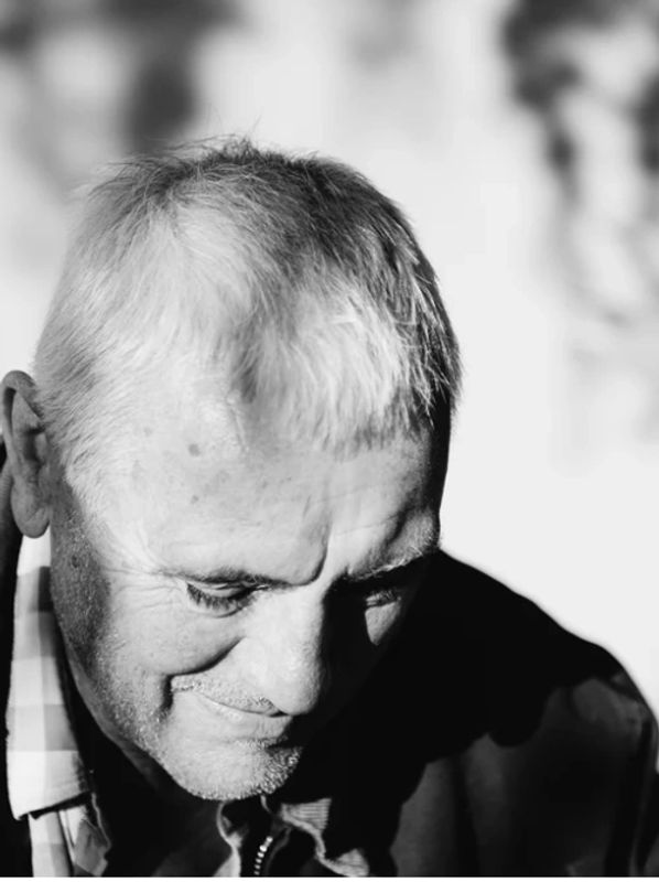 Black and white portrait of an elderly man looking down thoughtfully.