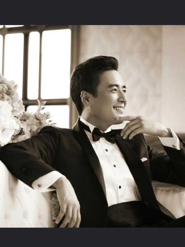 A man in a tuxedo sitting on top of a chair.