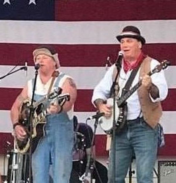 Two men performing music with American flag backdrop.