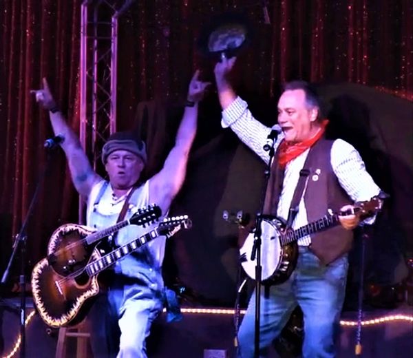 Two musicians performing energetically on stage.
