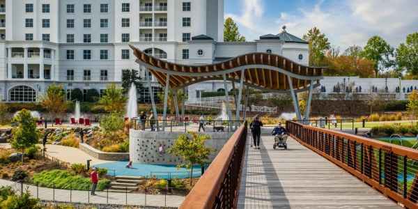 People enjoy a walk on a wooden bridge in a modern park area.
