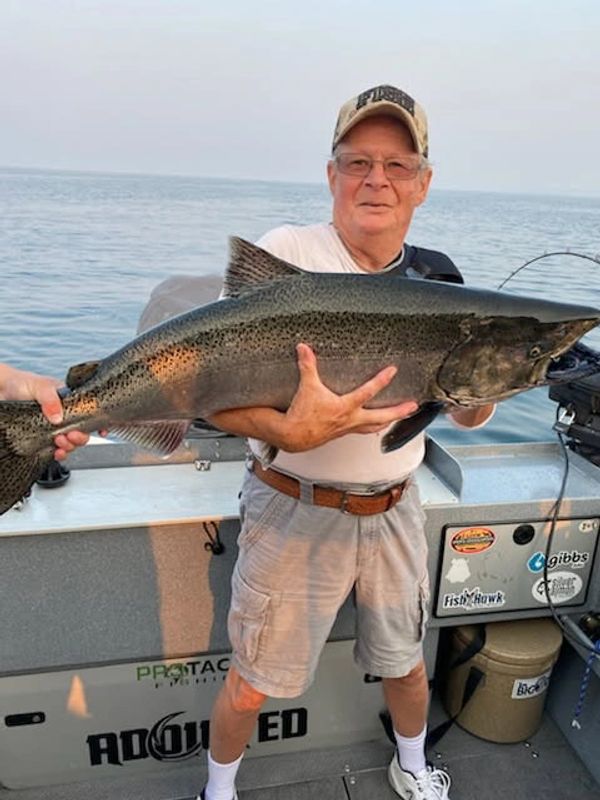 Man proudly holding a huge fish on a boat at sea.