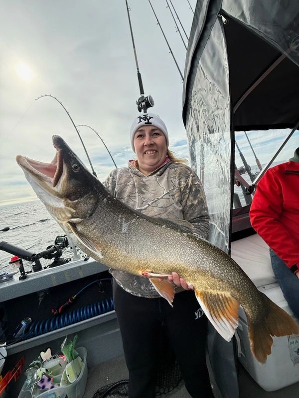 Woman on a boat holding a large fish with a smile.