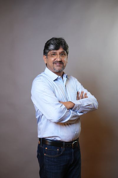 Man in blue shirt with arms crossed, smiling.