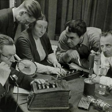 Group of people examining early telecommunication devices.
