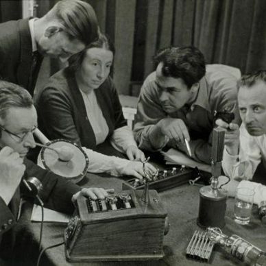 Group of people examining early telecommunication devices.