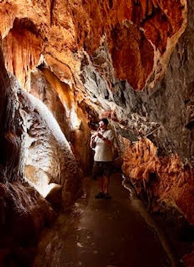 A person exploring a dimly lit cave with rocky walls.