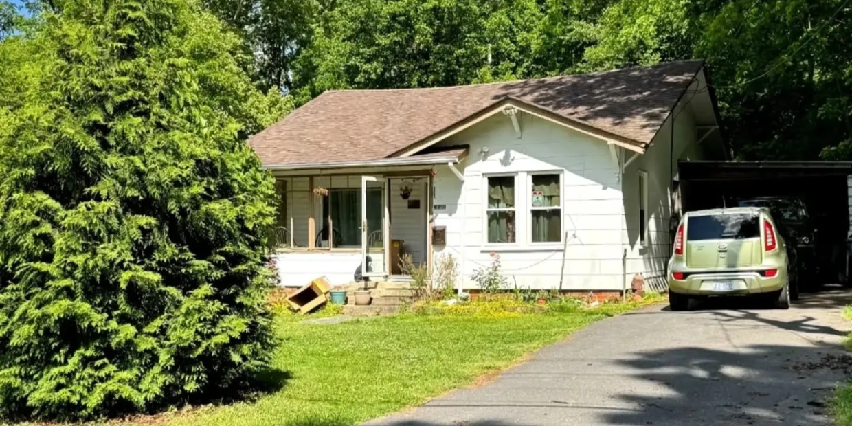 Small white house with a driveway and car.
