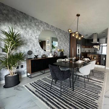 Modern dining room with black table, mixed chairs, and large round mirror.