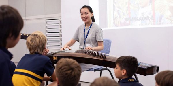 Teacher plays traditional string instrument for children.