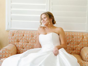 Bride sitting on an orange-patterned couch, looking serene and happy.