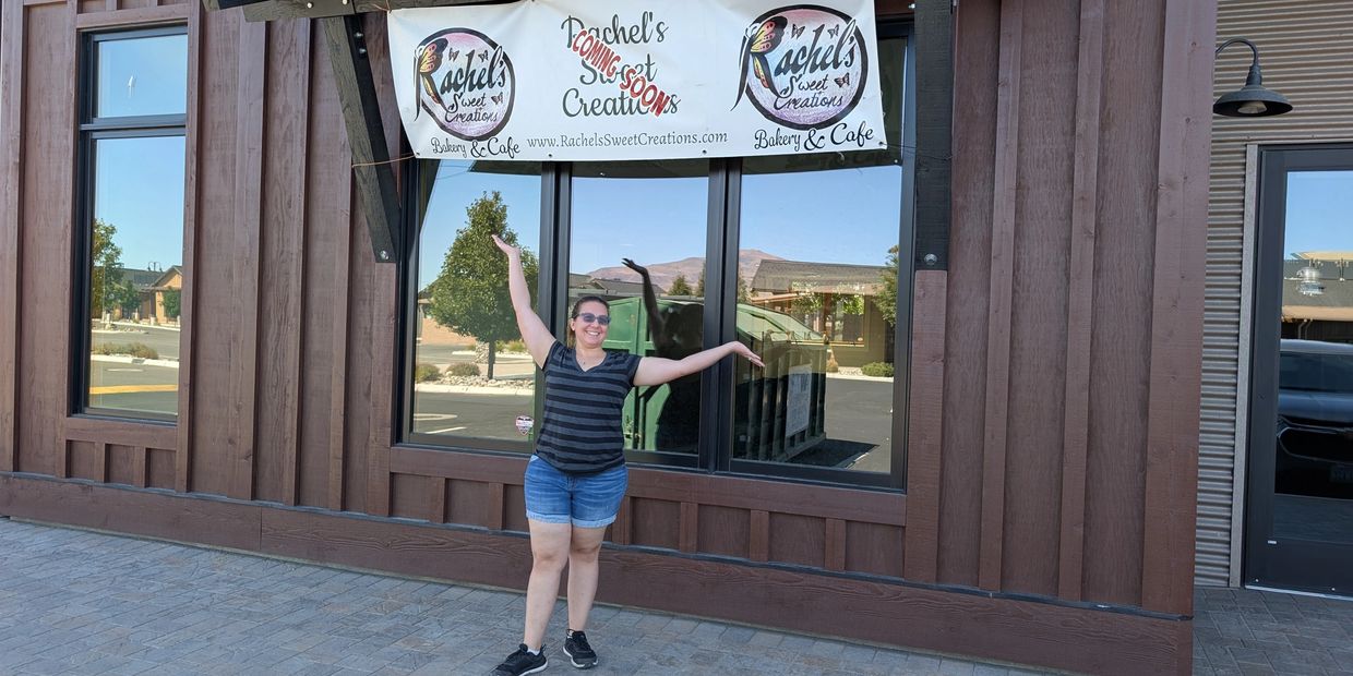 Woman excitedly posing outside Rachel's Sweet Creations bakery.
