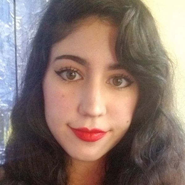 Close-up of a woman with red lipstick and wavy dark hair.