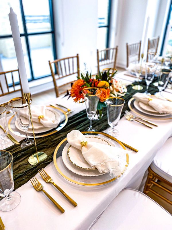Closeup of table setting with white and gold china, candlesticks, and fall flowers