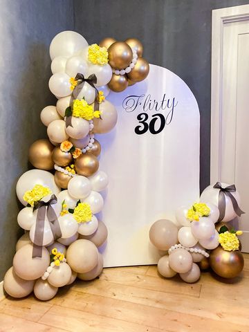 White arched backdrop with tan white and gold balloons attached