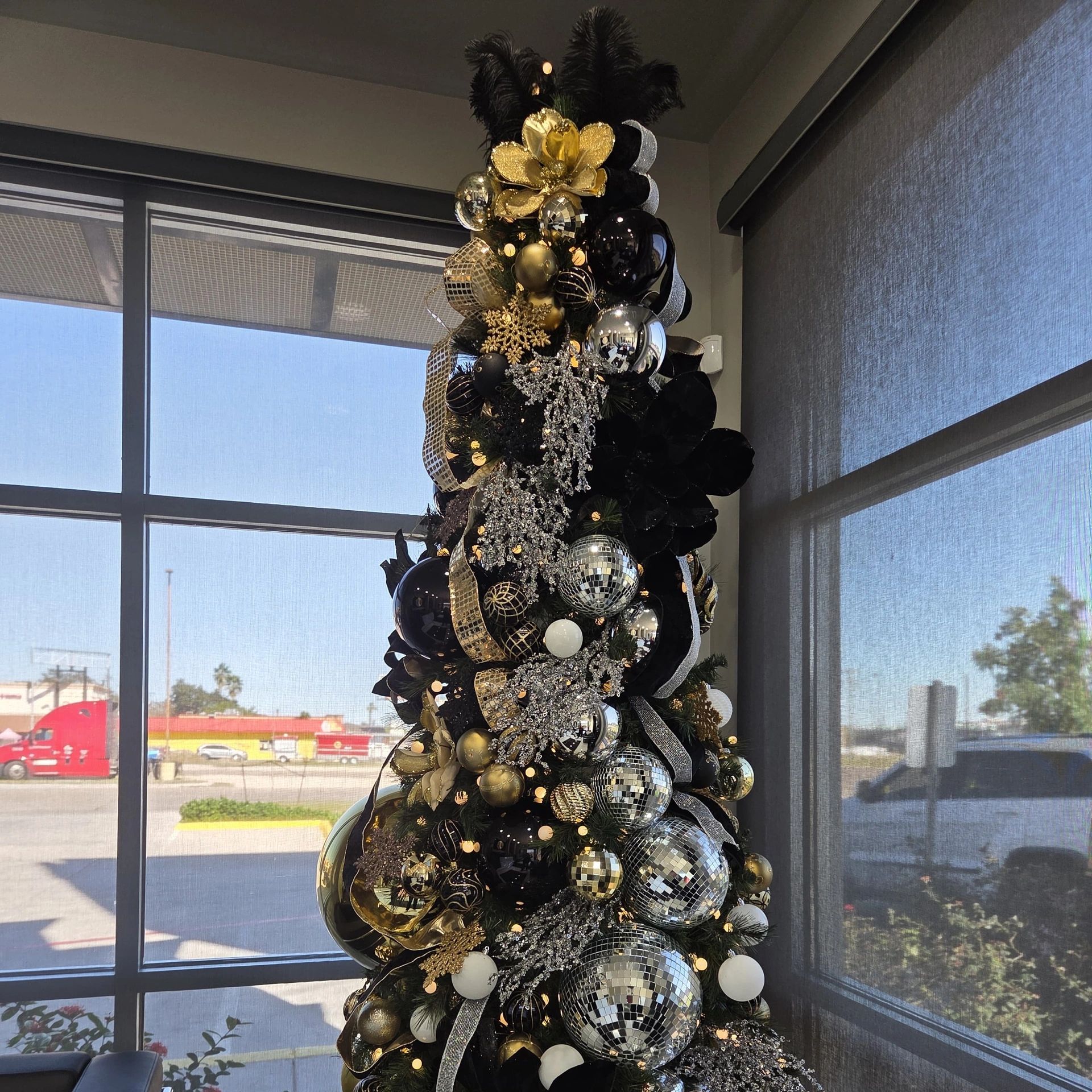 Christmas tree decorated with black, gold, and silver ornaments.