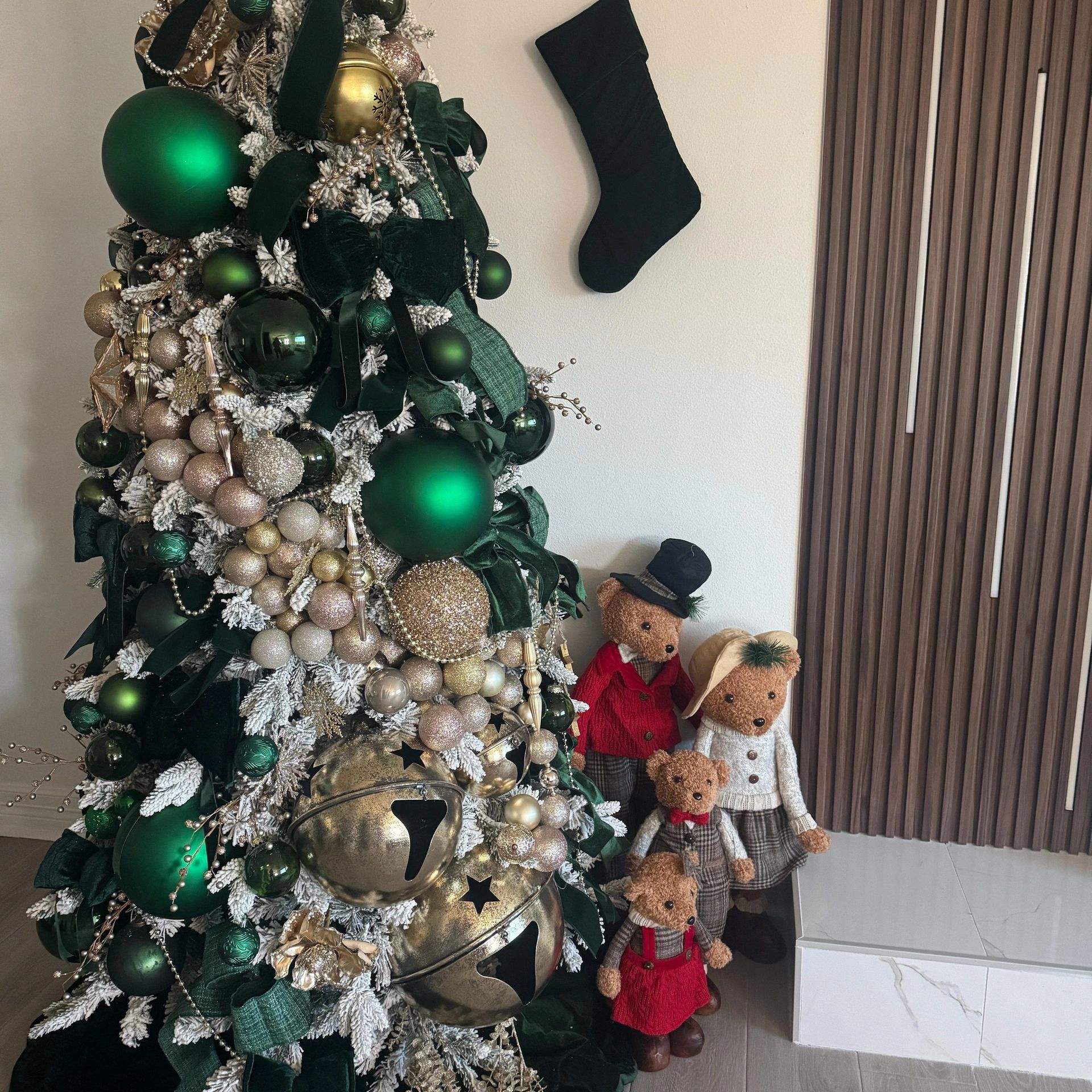 Christmas tree with green and gold ornaments and teddy bears.