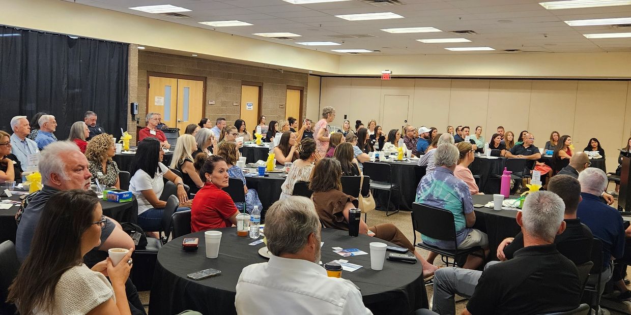 A large group attentively listening to a speaker in a conference room.