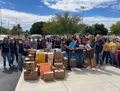 Group of people outdoors with many packed boxes, likely for donation or distribution.
