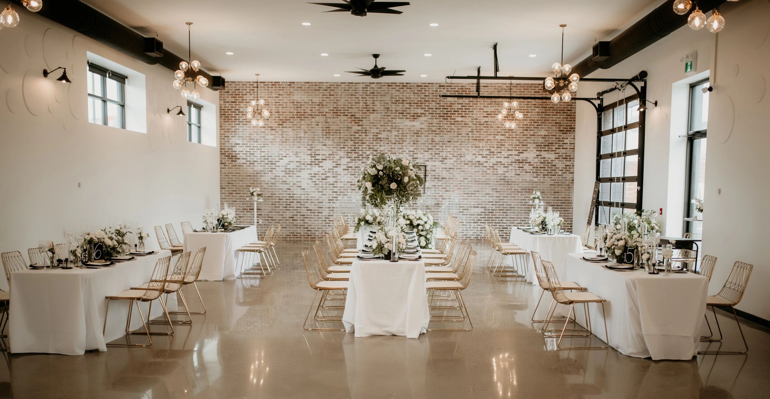 Wedding venue. Rectangular tables. Wedding reception. Wedding flowers. Brick wall. Loft venue.