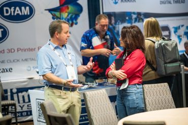 Two people having a conversation at a trade show booth.