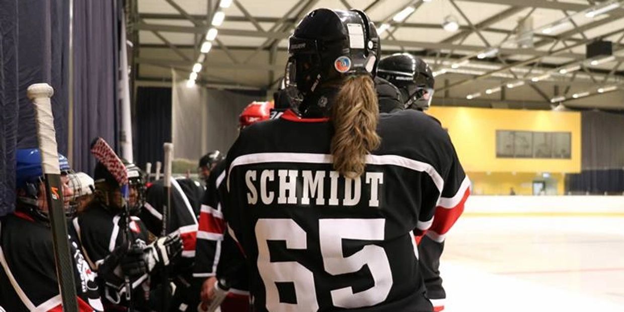 Ice hockey players in black jerseys on the bench during a game.
