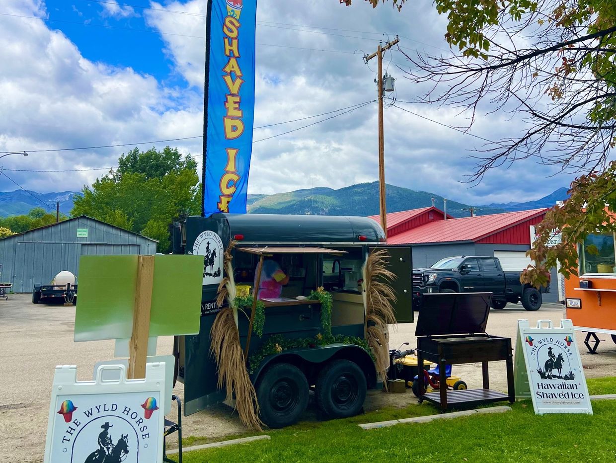 A small shaved ice stand with mountain views and cloudy skies.