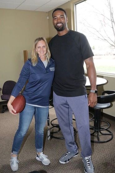 Two people standing together inside a room, one holding a football.