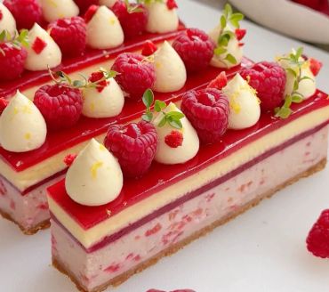 Elegant raspberry mousse cake slices with cream and fresh raspberries.
