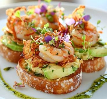 Gourmet shrimp appetizer on toasted bread with avocado and microgreens.