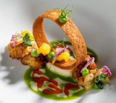 Artistic gourmet dish with vibrant garnishes and a crispy ring centerpiece.
