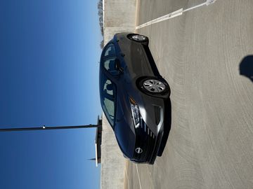 A gray Nissan sedan parked on a rooftop under clear blue sky.