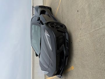 Black sports car parked on rooftop under cloudy sky.