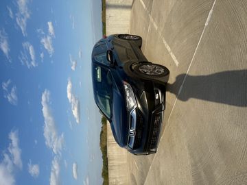 Black Honda CR-V parked on a rooftop under a blue sky with scattered clouds.